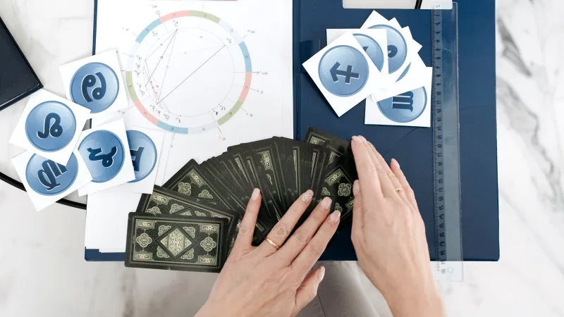 Astroloji haritası ve kartların üzerinde duran eller